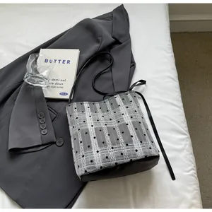 Détail du sac seau à carreaux gris avec pois noirs, rayures dentelle et nœud latéral