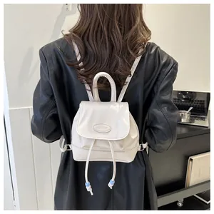 Detail of a beige mini backpack with drawstring closure and stylish beaded fringe tassel