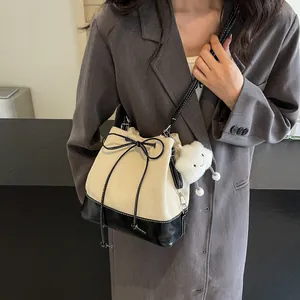 Minimalist two-tone canvas bucket bag with drawstring and cloud plush charm detail