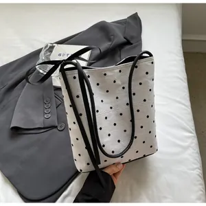 Détail du sac seau blanc à pois avec texture en dentelle et nœud en ruban noir