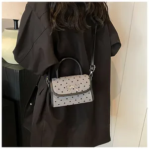 Close-up of gray shoulder bag featuring black heart prints and a silver bow detail