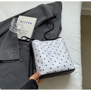 Détail d'un sac seau à pois blancs avec dentelle noire et nœud en ruban élégant