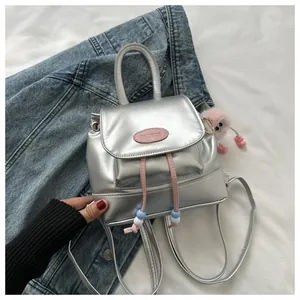 Detail of silver metallic mini backpack with pink drawstring and plush charm accessory