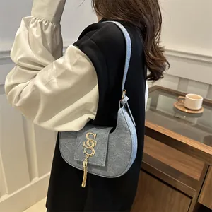 Sac à bandoulière croissant en denim bleu avec logo S doré et glands métalliques