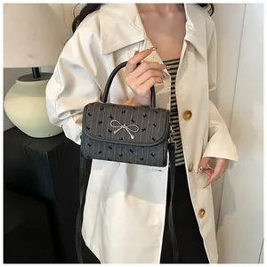 Close-up of a dark grey polka dot bow handbag with silver metallic buckle on a coat