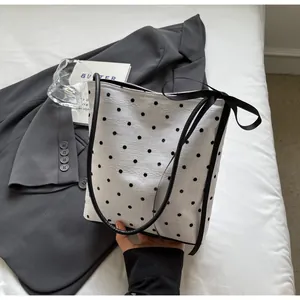 Détail du sac cabas blanc à pois avec nœud en ruban noir et fini texturé