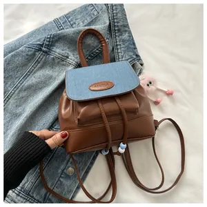 Detail of mini backpack with brown leather, denim flap and a cute pink plush charm
