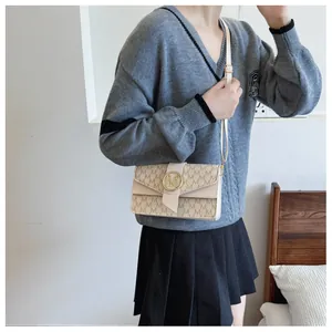 Detailed view of beige monogram PU leather crossbody bag with golden metal M-shaped buckle