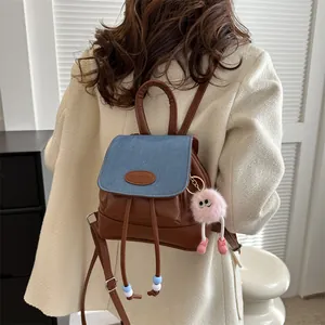 Retro mini backpack with brown PU leather and blue denim flap shown on a model in white coat