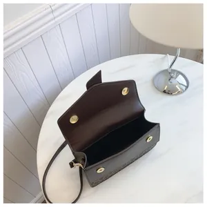 Detail of coffee brown PU leather bag showing magnetic gold buckle and M-pattern lining