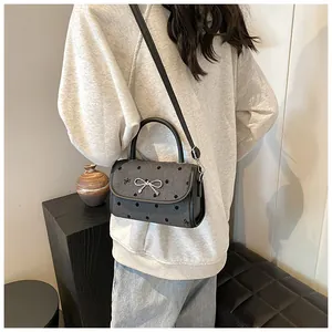Detailed view of gray denim polka dot bag with silver bow on a model shoulder
