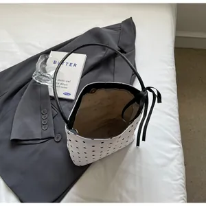 Détail du sac seau blanc à pois noirs avec de fines anses et un nœud décoratif élégant