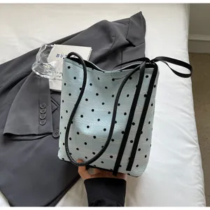 Détail du sac fourre-tout bleu clair à pois avec ruban noir sur fond de blazer gris