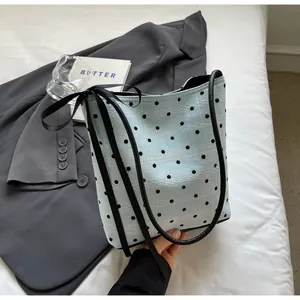 Détail du sac seau bleu clair à pois avec nœud en ruban noir et texture dentelle
