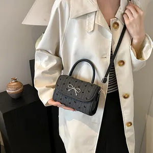 Chic dark gray polka dot crossbody bag with a silver bow clasp for modern women
