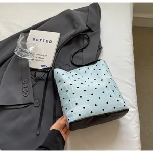 Détail du sac seau bleu clair à pois avec base en cuir noir et décoration de nœud