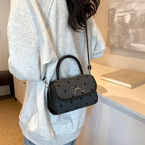 Chic gray polka dot handbag with bow embroidery and metallic clasp on a shoulder strap
