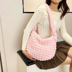 Detail of pink bubble texture shoulder bag with pleated design worn by a model