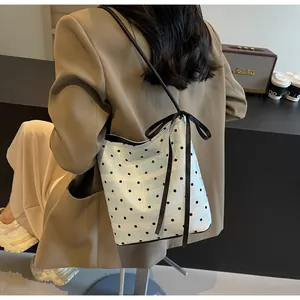 Détail du sac seau bleu clair à pois avec texture dentelle et pendentif en nœud