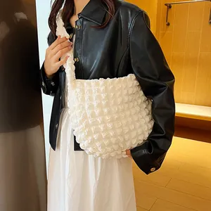 Detail shot of white popcorn texture fabric on a soft slouchy shoulder tote bag
