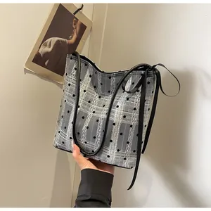 Détail d'un sac seau chic à pois et carreaux avec des rubans décoratifs en soie noire
