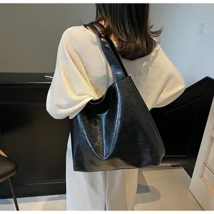 Detail of crinkled texture black tote bag worn by a model in a minimalist indoor setting
