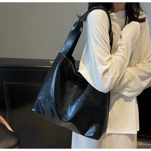 Detailed texture of black glossy wrinkled faux leather tote bag with wide shoulder strap