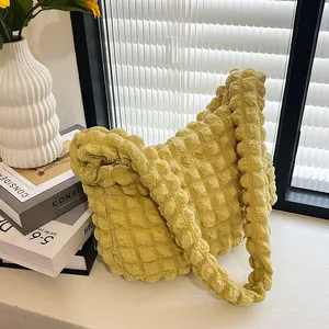 Detailed macro view of the popcorn texture and wide strap on yellow shoulder bag