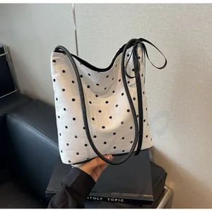 Détail d'un sac cabas en toile blanche à pois noirs avec un nœud papillon élégant