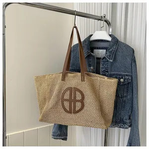 Détail du sac fourre-tout en paille tressée avec logo HB en cuir et anses marrons
