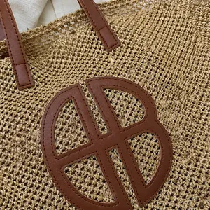 Detail showing the woven straw texture and premium brown leather circular emblem on the bag