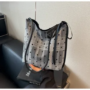 Détail du sac seau tendance en dentelle à pois noirs et blancs sur un canapé en cuir