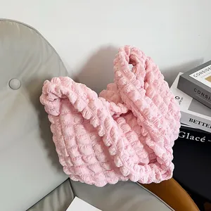 Detail of light pink bubble textured hobo bag on a leather seat with soft lighting