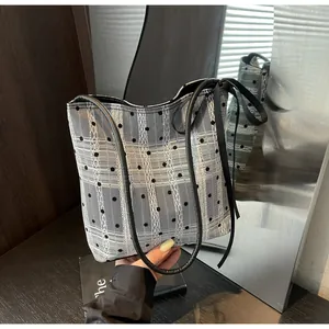 Détail du sac cabas en maille à carreaux avec pois et rubans décoratifs noirs