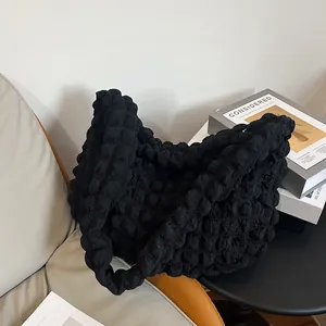 Detail of black puff tote bag with bubble texture on a beige leather chair