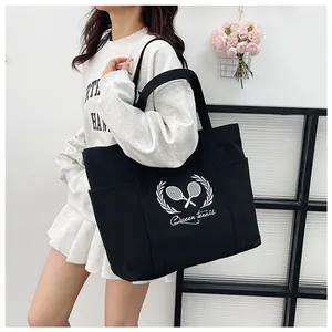 Detail of black tennis tote bag featuring Queen Tennis print and functional side pockets