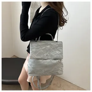 Detailed view of silver backpack featuring metallic wrinkled texture and oval metal twist lock