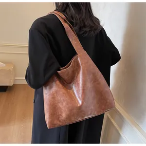 Detailed view of the large brown tote bag with retro leather texture worn with a black coat
