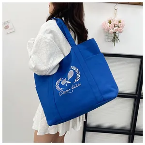 Detail of navy blue canvas tote bag with Queen tennis print and a functional side pocket