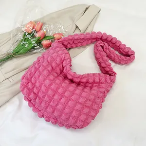 Detail of bright pink popcorn texture shoulder bag next to fresh pink tulips