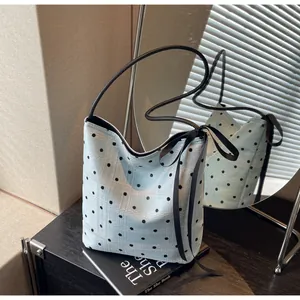 Détail du sac seau bleu clair à pois noirs avec un nœud décoratif en ruban noir
