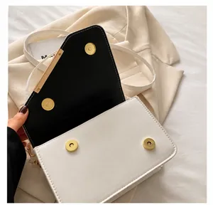 Detail of dual golden magnetic closures and fine stitching on a monochrome handbag