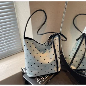 Détail du sac seau bleu clair à pois avec texture en dentelle et nœud en ruban noir