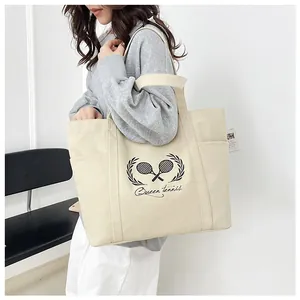 Detail of canvas tote bag side pocket holding a water bottle with tennis print detail