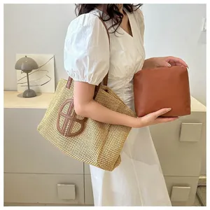 Détail d'un grand sac cabas en paille tressée avec pochette en cuir et logo chic