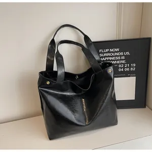 Macro detail of black glossy wrinkled faux leather tote bag with gold snap button closure