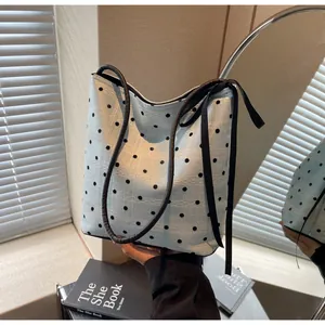 Détail du sac cabas bleu clair à pois avec texture dentelle et élégants rubans noirs
