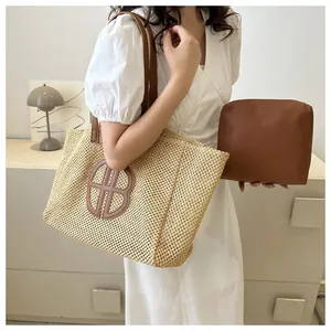 Détail du sac cabas en paille tissée avec logo B en cuir marron et pochette interne