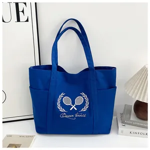 Detail of navy canvas tote bag featuring white tennis racket print and open side pockets