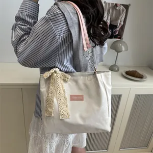 Large cream tote bag with oversized lace bow and pink chain strap in lifestyle setting